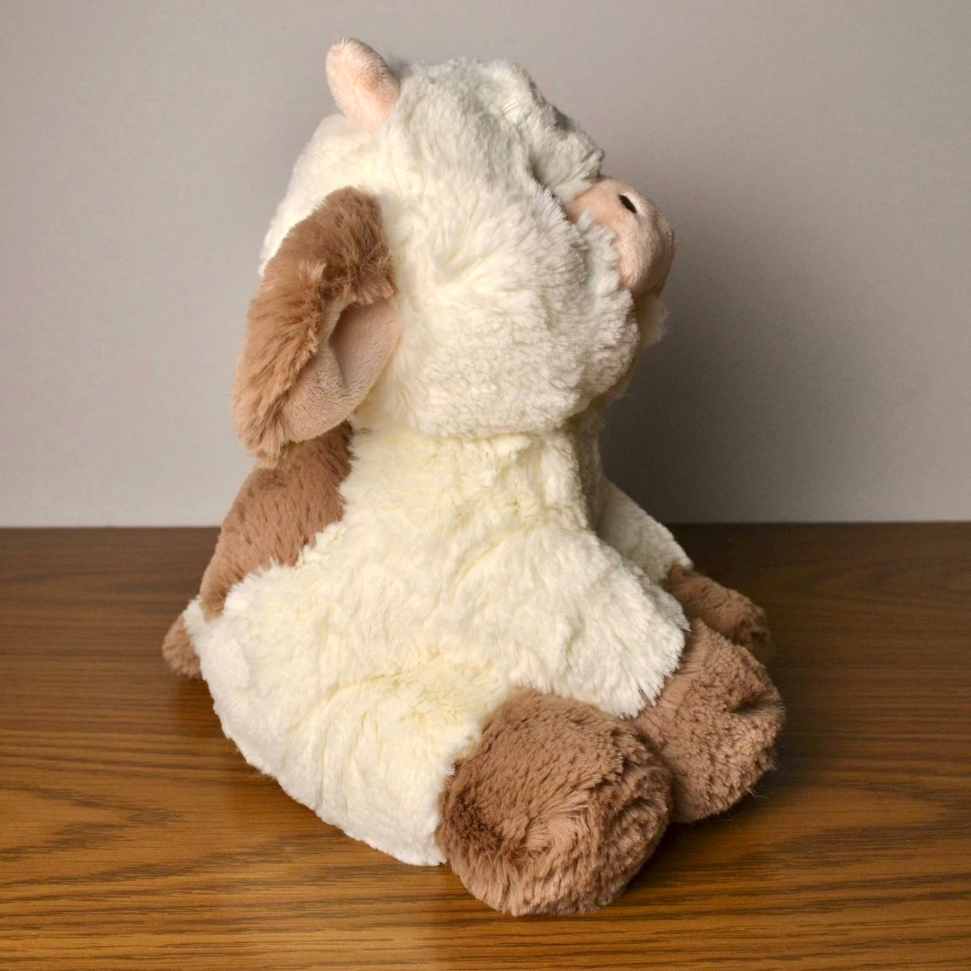 Plush  cow toy on a wooden surface with a neutral background