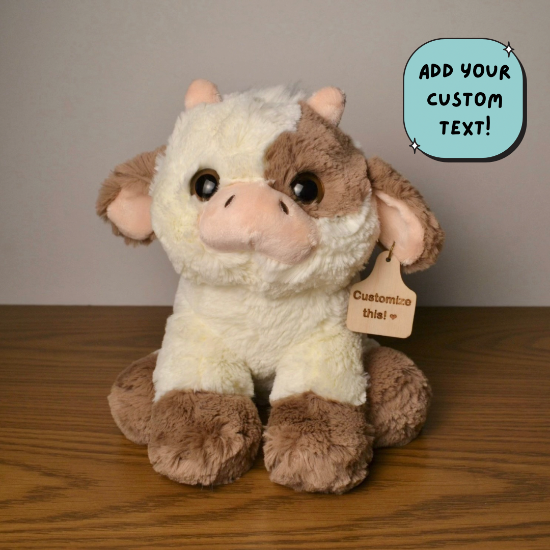 Plush cow toy with customizable text tag on a wooden surface